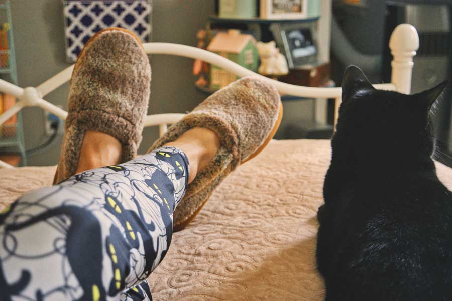 wearing cozy slippers on bed with cat